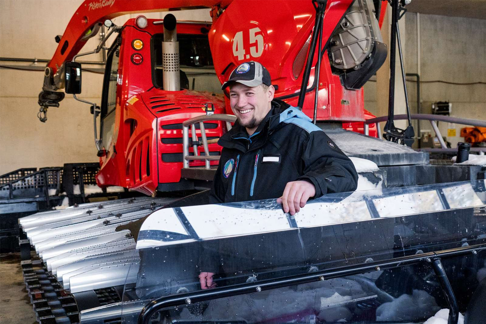 Ein Pistenbullyfahrer, im Hintegrund die Pistenraupe