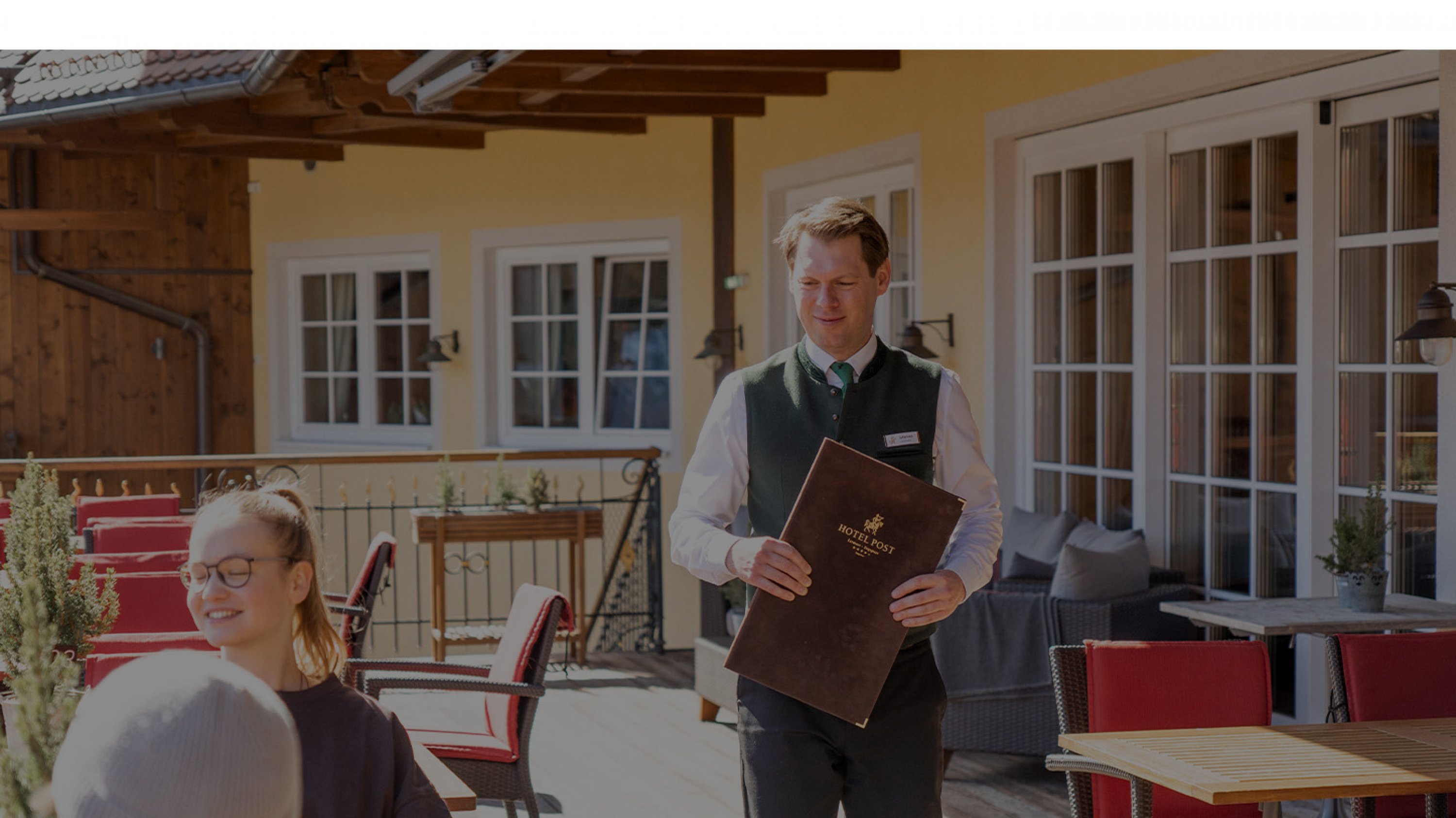A waiter carries a menu in his hand and approaches a table