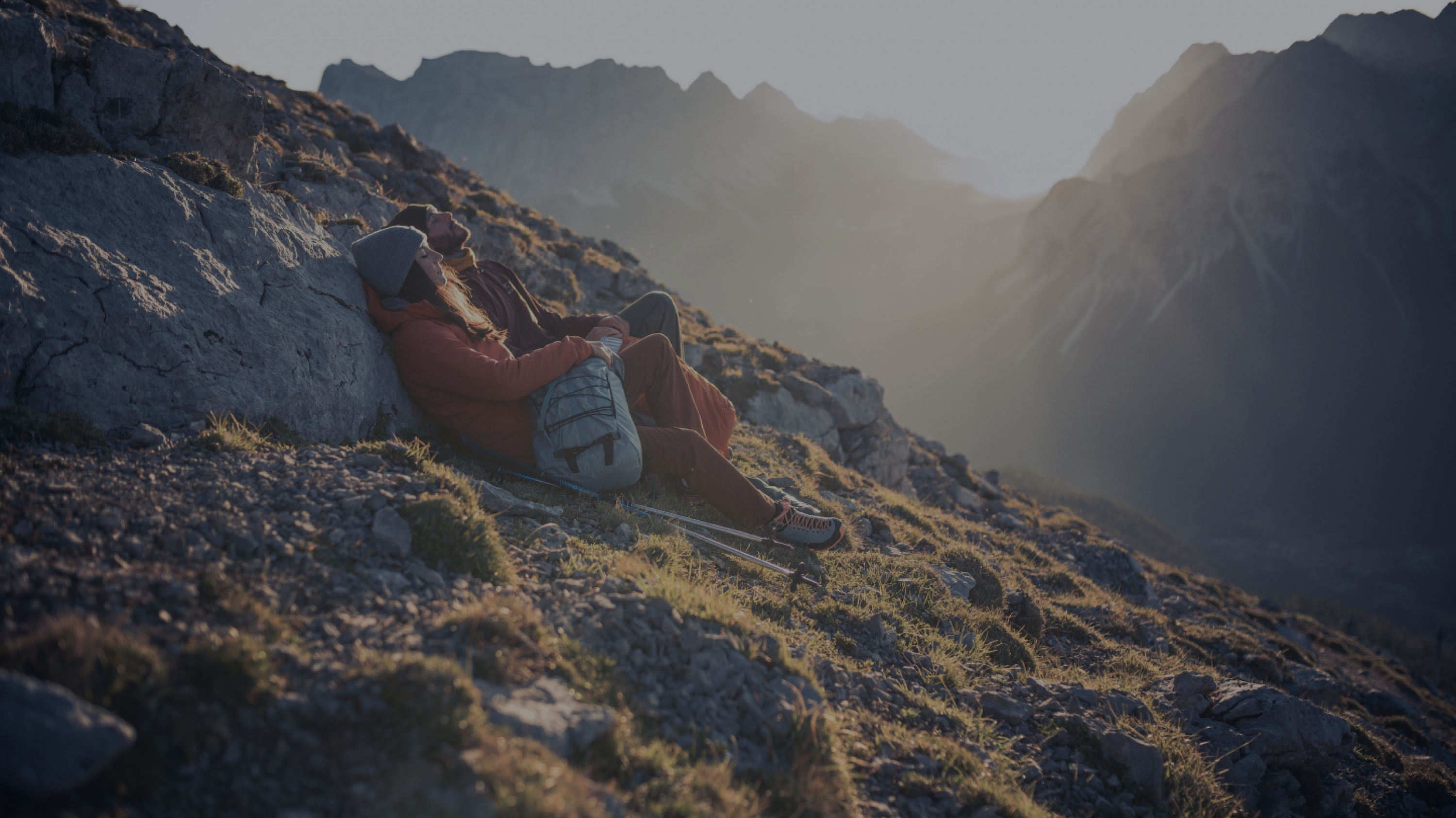 Eine Frau und ein Mann sitzen in der Morgensonne am Berg und entspannen sich