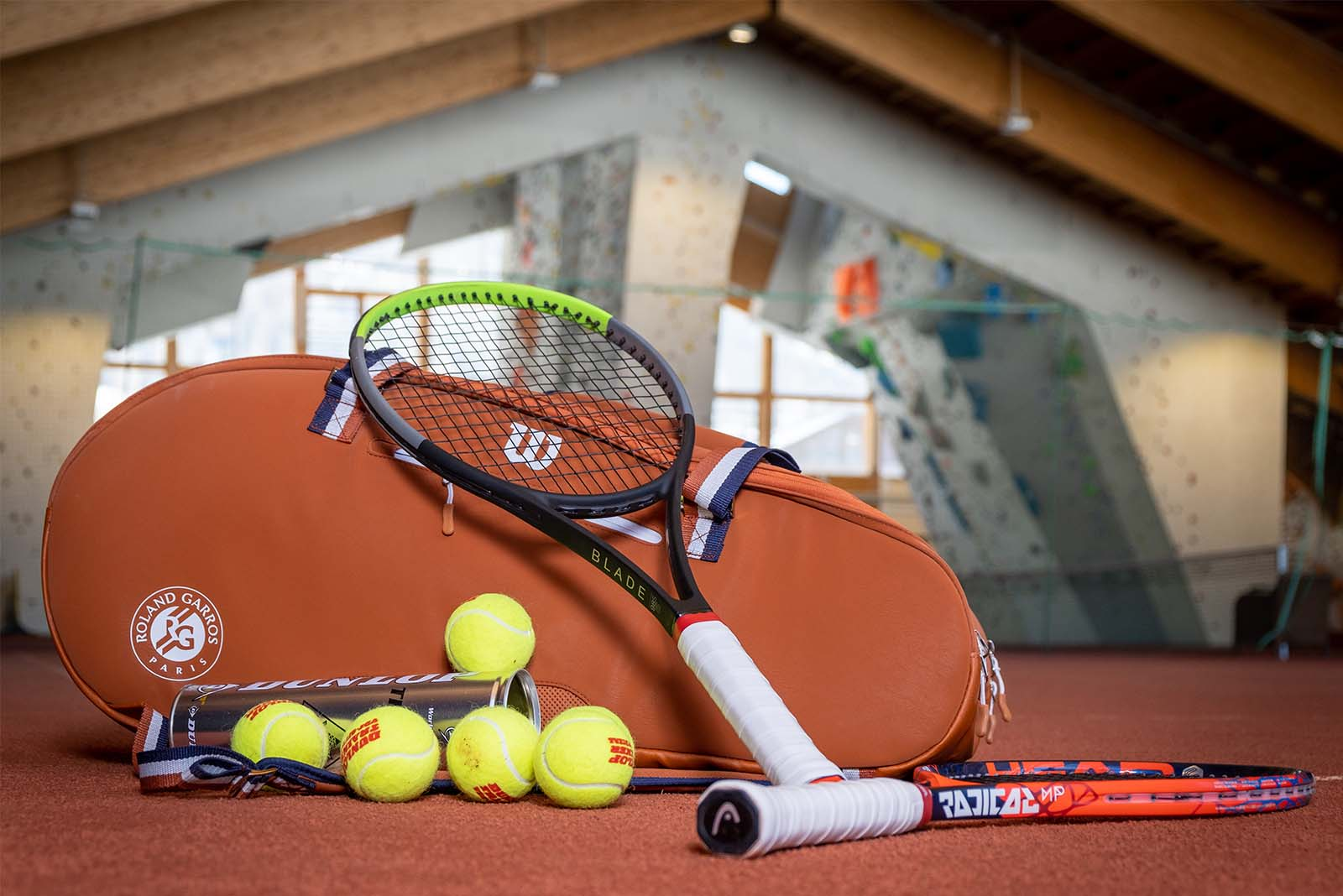 Tennis rackets and tennis balls lie nicely arranged in a indoor tennis court