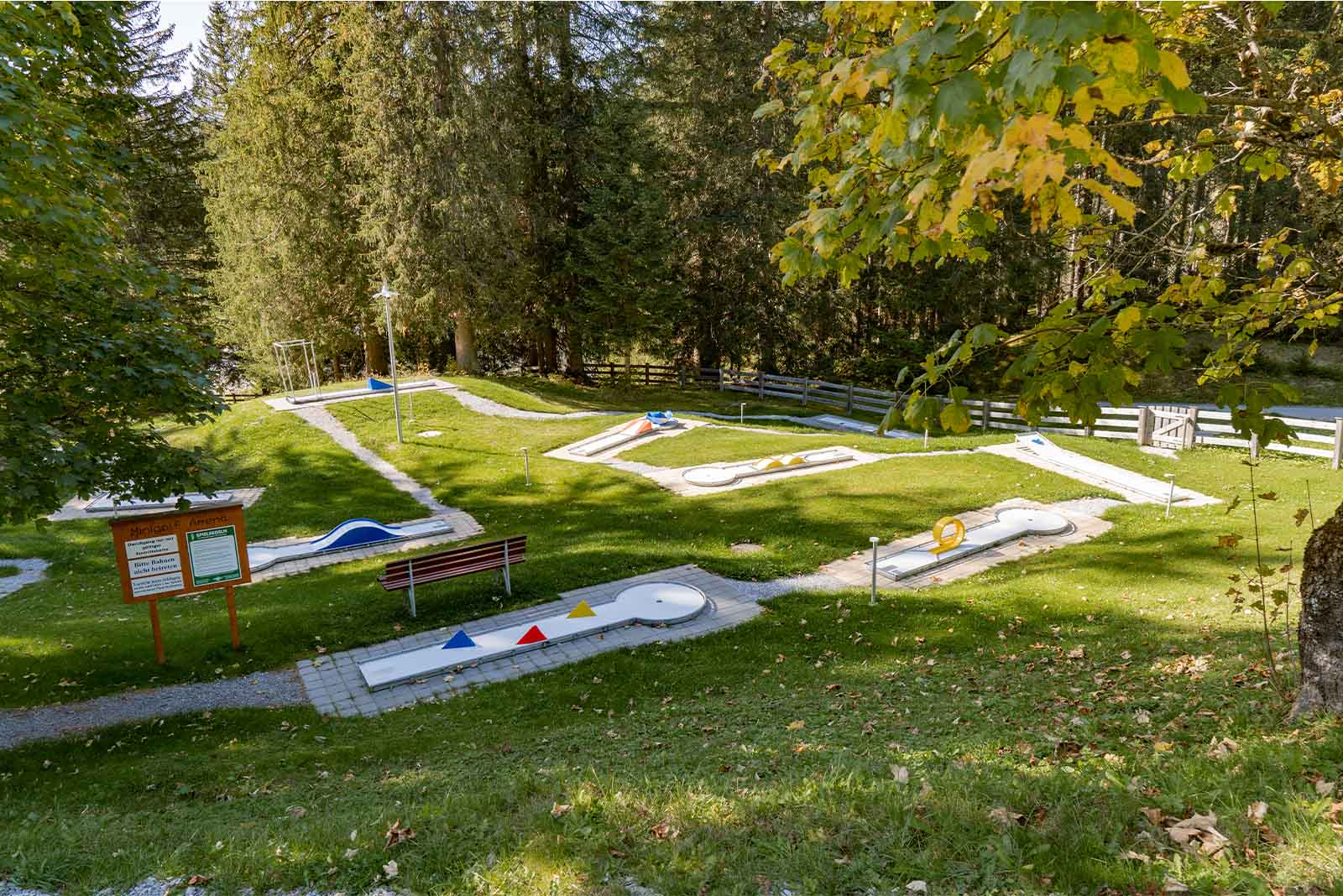 Several beautiful minigolf courses, a well-tended green lawn in between, forest in the background