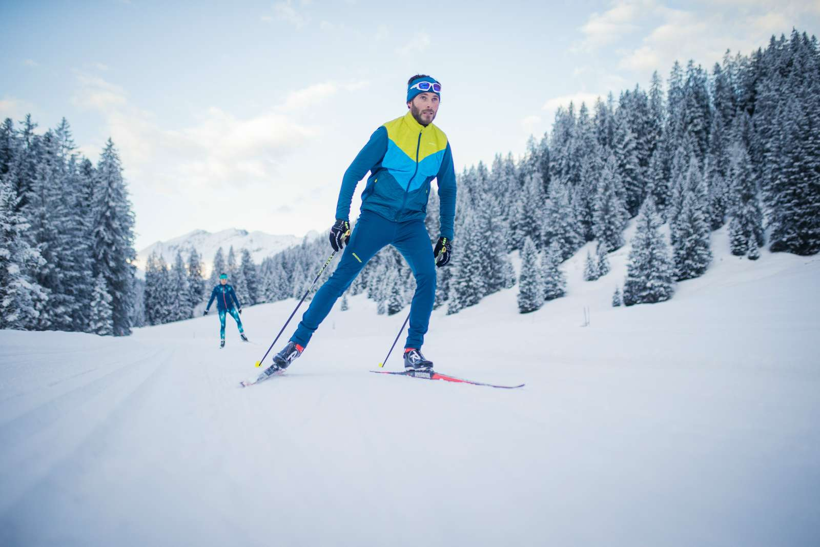 Two persons are doing cross-country skiing on a cross-country ski run in the middle of a winter landscape
